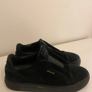 Svarta sneakers från Axel Arigato -  Svarta sneakers från Axel Arigato i mocka med diskret guldtext på sidan. Storlek 40. Mycket bra skick då de knappt är andvända.