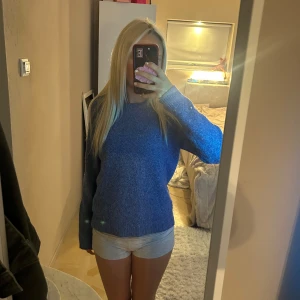 Blå stickad tröja med rund hals - Mysig blå stickad tröja med rund hals och långa ärmar. Perfekt för kyligare dagar och enkel att matcha med olika outfits. Tröjan har en klassisk passform och är superbekväm att bära.