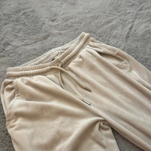 Beiga mjukisbyxor i velour - Supermjuka beiga mjukisbyxor i velour från C&A Studio. Byxorna har resår och snörning i midjan, två sidofickor fram och två bakfickor. Perfekta för chill dagar och riktigt sköna att ha på sig.