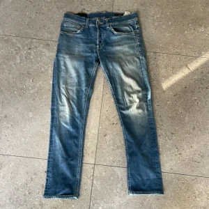 Blå skinny jeans från Dondup - Säljer ett par snygga blå skinny jeans från Dondup, modell George. Jeansen har klassisk femficksdesign, ljusa slitningar och smal passform. Tillverkade i mjuk bomullsdenim med stretch för extra komfort. Perfekta för dig som gillar en modern och tight look.