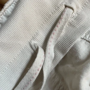 Vita linnebyxor med snörning, stl 34 - Snygga och luftiga vita linnebyxor med bred ribbad midja och snörning framtill. Byxorna har raka ben och sidfickor, perfekta för en chill och avslappnad stil. Materialet är linne som ger en skön känsla och passar grymt bra till varmare dagar. (Måste strykas kommer skrynklas till när jag skickar men kan stryka innan ändå om önskas)