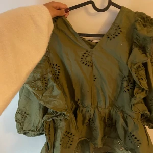 Grön broderad klänning från ONLY - Supersöt grön klänning från ONLY med broderade detaljer och v-ringning. Klänningen har puffiga korta ärmar och markerad midja. Perfekt för dig som gillar romantiska vibes och snygga detaljer.