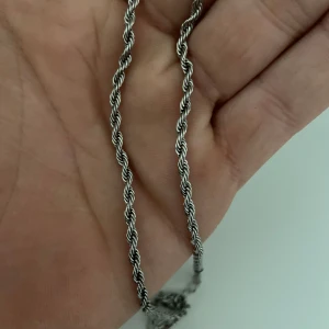 Tvinnad silver halskedja - Säljer en stilren halskedja med tvinnad design i silverfärg. Kedjan har en klassisk look och passar perfekt om du gillar enkla men snygga smycken. Materialet är metall med en glansig finish och kedjan är lagom tjock för att synas utan att ta över.
