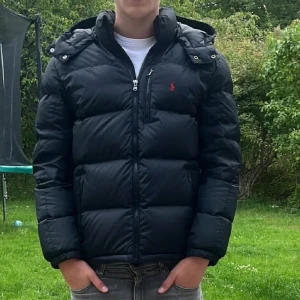Svart pufferjacka Polo Ralph Lauren XL - Säljer en svart pufferjacka från Polo Ralph Lauren i storlek XL men pass S/M jackan är i nytt skick bara andvänd fåtal gånger nypris runt 6000 mitt pris 1999 skriv vid minsta fundering😃