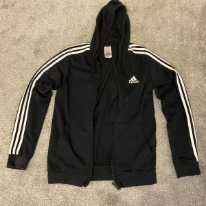 Svart Adidas hoodie  - Svart hoodie från Adidas. Perfekt för en sportig och avslappnad stil.