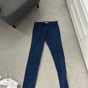 Mörkblå slim byxor från Zara - Snygga mörkblå byxor från Zara i slim fit-modell. Byxorna har klassisk femficksdesign, dragkedja och knapp framtill. Perfekta för dig som gillar en stilren look med smal passform. Materialet känns mjukt och följsamt.