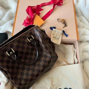 Louis Vuitton Damier handväska brun - Säljer en klassisk Louis Vuitton handväska i Damier-mönster.   fick väskan som present och jag har tyvärr ingen kvitto. Den är använd ett få tal gånger så är den i ny skick. Allting medföljer som ni ser på bilden 