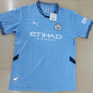 Manchester City matchtröja Puma L - Manchester Citys officiella matchtröja från Puma i ljusblått med mörkblå detaljer. Tröjan har korta ärmar, klubbmärke på bröstet och Etihad Airways-tryck framtill. Tillverkad i lätt och ventilerande funktionsmaterial, perfekt för fotboll eller supporterliv.