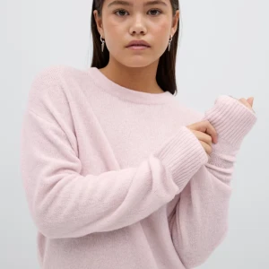 Ljusrosa stickad tröja med rund hals - Supermjuk ljusrosa stickad tröja med rund halsringning och långa ärmar. Tröjan har ribbade muddar vid ärmslut och nederkant, vilket ger en chill och avslappnad vibe. Perfekt att slänga på sig när det är kallt ute.