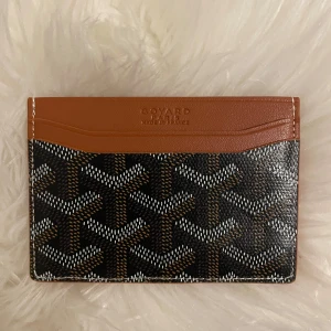 Goy4rd plånbok med klassiskt mönster - Säljer en snygg Goy4rd plånbok i brunt och svart med det ikoniska Goy4rd-mönstret. Plånboken är i skinn och har flera kortfack. Perfekt för dig som vill ha något stilrent och exklusivt i fickan. Kommer med originalbox och kvitto.