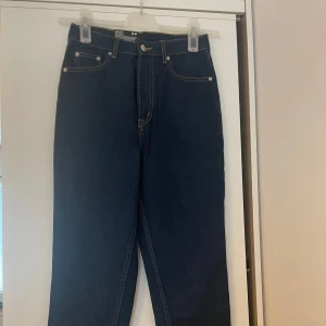 Mörkblå mom jeans från Divided - Mörkblå mom jeans med hög midja och ankellängd från Divided. Klassisk femficksmodell med raka ben och kontrastsömmar. 