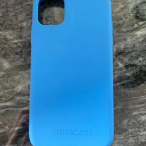 YOURCASE Blå Mobilskal - Snyggt blått mobilskal från YOURCASE, designat för iPhone med kameraöppning. Skalet är i gott skick med mindre tecken på användning invändigt. Ger bra skydd och stil till din mobil. Perfekt för dig som vill ha ett fräscht och tåligt skal.
