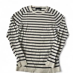 Randig tröja från Jack & Jones | M - Snygg långärmad tröja från Jack & Jones i vitt med marinblå ränder. Klassisk rund halsringning och ribbade muddar. Tillverkad i mjuk bomull, perfekt för en chill och stilren look.