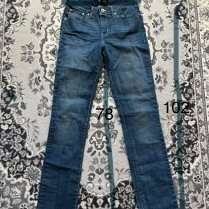 Levi's Demi Curve Straight jeans blå - Snygga blå Levi's Demi Curve Straight jeans med klassisk femficksdesign och raka ben. Jeansen har normal midja och är tillverkade i mjukt denimtyg med subtila slitningar. Perfekta för dig som gillar en tidlös och clean look.