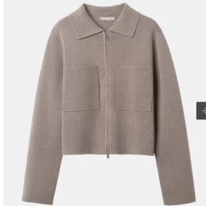Beige stickad overshirt med dragkedja - Snygg beige stickad overshirt från Åhlens med rak passform, två stora bröstfickor och dragkedja framtill. Jackan har klassisk krage och är långärmad, perfekt för lager-på-lager. Stilren och enkel att matcha till allt. Helt ny med lappar