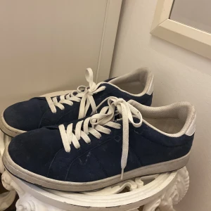 Blå sneakers från Race Marine, strl 44 - Snygga blå sneakers från Race Marine i mocka med vita detaljer och snörning. Skorna har vit sula och vit insida, samt klassisk rund tå. Perfekta för dig som gillar en stilren och sportig look.