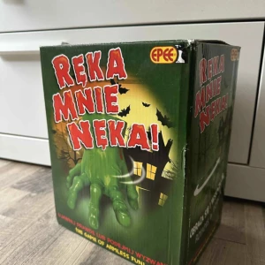Ręka Mnie Nęka! (The Game of Armless Fun) - Rolig och skrämmande elektronisk leksak från Epee. Lådan innehåller en grön, rörlig hand som används i spelet. Förpackningen är i gott skick med mindre slitage i hörnen. Perfekt för Halloween eller familjespelkvällar.