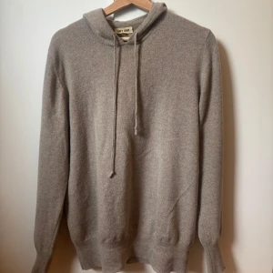 Beige hoodie i kashmir från Soft Goat - Säljer en stilren beige hoodie från Soft Goat i mjuk kashmir. Litet slitage på tröjan vid halsen, men knappt något man märker och väldigt lätt att åtgärda om man vill. Storlek L men sitter som M.