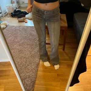 Grå bootcut jeans med fickor low waist  - Säljer ett par gråa jeans med bootcut-modell och stora framfickor. Byxorna har låg midja och är i ett mjukt denimtyg. Snygga sömmar och klassisk femficksdesign. Perfekta om du gillar en avslappnad men ändå trendig look.