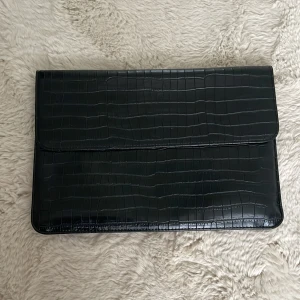 Datorväska - En väldigt stilren svart datorväska som går att matcha med allt. Stängs igen med ett magnetiskt lock och är väldigt praktisk för att bära med sig dator eller mappar.