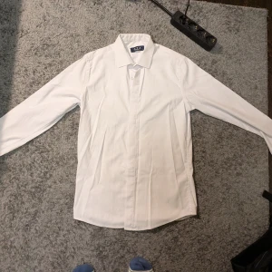 Vit skjorta från ATZ Club Exclusive - Klassisk vit skjorta från ATZ Club Exclusive i storlek S. Materialet känns mjukt och lätt, troligen bomull.