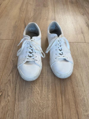 Vita klassiska sneakers från Pier One - Säljer ett par vita sneakers med låg profil. Skorna har klassisk snörning och en platt sula. Perfekta för dig som gillar en clean och enkel stil. Passar till det mesta och är riktigt bekväma. Perfekta till exempel till studenten.