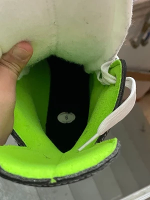 Svarta och vita hockeyskridskor strl 6 - Säljer ett par Bauer hockeyskridskor i svart och vitt med neongrön insida. Skridskorna har vita snören och robust plastkappa för extra stöd. Perfekta för isträning eller match. Klassisk design och bekväm passform.