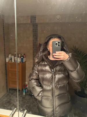 Mörkgrå puffer dunjacka med huva - Säljer en snygg mörkgrå puffer dunjacka med huva. Jackan har dragkedja framtill och två fickor på sidorna. Perfekt för kalla dagar och ger en cool, oversized look. Passar dig som vill ha en varm och trendig vinterjacka. Jackan är nytvättad!