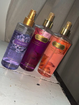 Victoria's Secret body mists 3-pack - Tre body mists från Victoria's Secret: Love Spell (lila), Mango Temptation (rosa/röd) och Such a Flirt (aprikos/rosa). Flaskorna är genomskinliga med guldiga spraymunstycken och färgglada etiketter. Perfekta för dig som gillar fruktiga och blommiga dofter. Alla tre för priset som står 💕💕