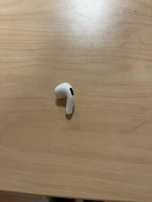 Apple AirPods 4 vänster hörlur - Säljer en vänster AirPods Pro hörlur från Apple. Den är vit med en stilren, kompakt design och har svarta detaljer. Hörluren är tillverkad i plast och har den klassiska AirPods 4 -formen som sitter bekvämt i örat.