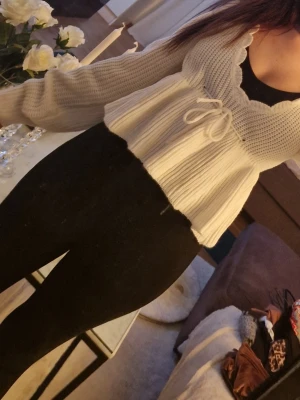 vit ribbad tröja med knytband - Söt vit tröja med ribbad struktur och knytband. Tröjan har långa ärmar och volangkant nedtill. 