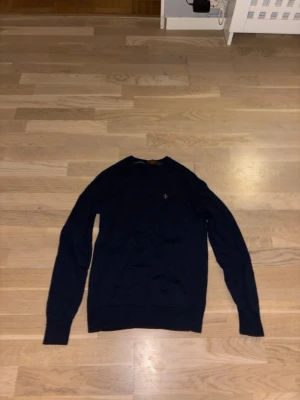 Mörkblå merinoulltröja Morris XS - Säljer en mörkblå tröja från Morris i 100% merinoull. Klassisk rund halsringning och diskret Morris-logga broderad på bröstet. Tröjan har lång ärm och ribbade muddar vid ärmslut och nederkant. Perfekt för dig som gillar stilrena och tidlösa plagg. Lite liten i storleken men passar fortfarande XS, pris kan diskuteras!