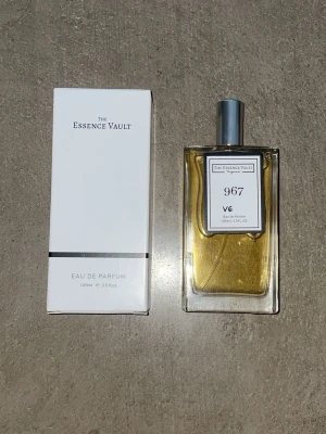 The Essence Vault 967 Eau de Parfum - The Essence Vault 967 V6 Eau de Parfum är en elegant parfym i en stilren, rektangulär glasflaska med silverfärgad kork. Flaskan rymmer 100 ml och har en guldfärgad vätska. Kommer i en vit kartong med minimalistisk design. ( dupe på Tom Ford Vanilla s*x )