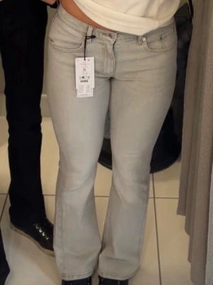 Ljusgrå bootcut jeans från Gina Tricot - Säljer ett par ljusgrå bootcut jeans från Gina Tricot. Jeansen har klassisk femficksdesign, normalhög midja och raka ben med lätt utsvängning nedtill. Perfekta för en trendig och avslappnad look.