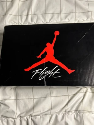 Nike Air Jordan 4 Vit/Grå Sneakers - Nike Air Jordan 4 sneakers i vitt och grått med svarta detaljer. Klassisk siluett med meshpaneler, snörning och synlig Air-sula. Ikonisk design med speckled gråa partier och Jumpman-logga. Perfekta för dig som vill sticka ut med stil.