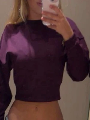 Vinröd croppad hoodie - Säljer en vinröd croppad hoodie med långa ärmar och bred mudd i nederkant. Hoodien har en enkel och clean design utan tryck eller detaljer. Perfekt till jeans eller mjukisbyxor för en chill look.