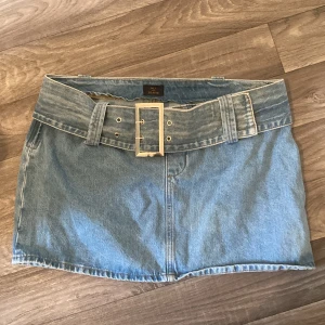Jeanskjol med bälte från NLY Jeans - Snygg lågmidjad jeanskjol i storlek 42 från NLY Jeans. Dragkedja i sidan och tillhörande jeans bälte. Knappast andvänd säljer då den är för stor. Orginalpris 449kr. (Pris kan diskuteras)