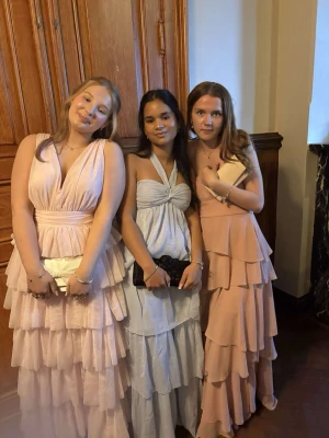 Ljusrosa lång balklänning med volanger - Superfin ljusrosa långklänning med flera lager volanger och axelbandslös design. Perfekt för bal eller student! Är ungefär 163 cm lång. Köpt förra året.