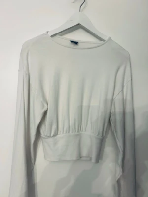 Vit croppad långärmad topp Gina Tricot - Säljer en vit croppad långärmad topp från Gina Tricot. Toppen har rund halsringning och bred resår i midjan för en snygg passform. Perfekt att styla med höga jeans eller kjol.