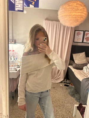 Off shoulder vit stickad tröja - Trendig off shoulder stickad tröja i vitt med bred krage som vilar över axlarna. Långärmad och i mjukt material, perfekt att styla med jeans för en avslappnad look. Original pris 500kr säljer för 100kr knappt använd.