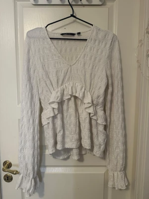 Blus  - Supersöt vit blus från VeroModa med volangdetaljer framtill. Blusen har v-ringning och långa ärmar med volang vid ärmslut. 💋