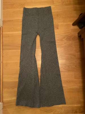 Grå ribbade yogapants i nyskick - Snygga grå yogapants i nyskick med ribbad struktur och bootcut-ben. Hög midja och stretchigt material som sitter skönt. Fick dem i julklapp men tyvärr var de för små för mig säljer de vidare. De är perfekta för dig som gillar en trendig och bekväm stil.