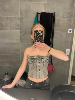 Grå denim topp - Grå jeans tubtopp med detaljer som fickor och knappar. stretchigt material. storlek XS, knappt använt men väldigt fin på sommaren till kjol. 