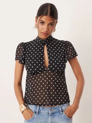 Prickig blus - SLUTSÅLD HOS ASOS!!!! Trendig svart blus med vita prickar, transparent material och korta puffärmar. Hög hals med nyckelhålsöppning framtill och knytband i nacken. Perfekt att styla med jeans för en cool look. Köpte två storlekar och orkar inte returnera utan säljer hellre vidare då den ändå är slutsåld hos ASOS.