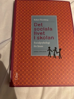 Det sociala livet i skolan - Boken 'Det sociala livet i skolan' av Robert Thornberg är en kursbok i socialpsykologi för lärare. Omslaget är rödorange med mönster och har en blå ruta med titeln. Andra upplagan. Perfekt för dig som pluggar pedagogik eller lärarutbildning. Få Markeringar förekommer 