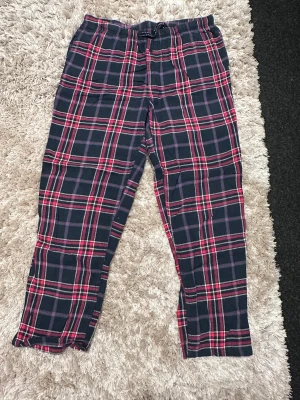 Rutig mjukisbyxa från Esmara - Säljer ett par sköna mjukisbyxor från Esmara med rött och mörkblått rutmönster. Byxorna har snörning i midjan och är gjorda i mjukt bomullsmaterial. Perfekta för chill hemma eller när du vill vara extra bekväm.