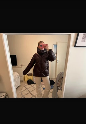 Massimo duitti jacka - Säljer en vinröd pufferjacka från Massimo dutti med stor, mysig huva och dragkedja framtill. Jackan har ett quiltat mönster och är lite oversized i modellen, perfekt för kalla dagar. Materialet är glansigt och känns riktigt skönt. Storlek M men passar mig som brukar ha S