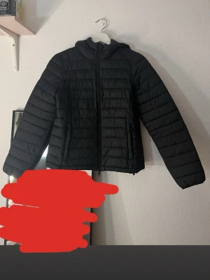 Svart pufferjacka från 157, XS - Säljer en svart pufferjacka från 157 i storlek XS. Jackan har huva, dragkedja framtill och två sidofickor med dragkedja. Den quiltade designen ger en clean look och jackan är perfekt för kyligare dagar.