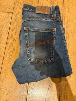 Nudie Jeans Grim Tim - Säljer ett par riktigt feta Nudie jeans av modellen Grim Tim som är i mycket bra skick. Sjukt bra passform och de sitter mer som W32 än W33 som står i byxorna. De är L32 i längd. Riktigt feta och mycket fräscha. Hör av er vid frågor.