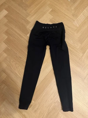 Svarta leggings från Relode - Svarta leggings från Relode med hög midja och tight passform. Perfekta för träning eller chill, med diskret logga på linningen. Mjukt och stretchigt material som sitter skönt hela dagen.